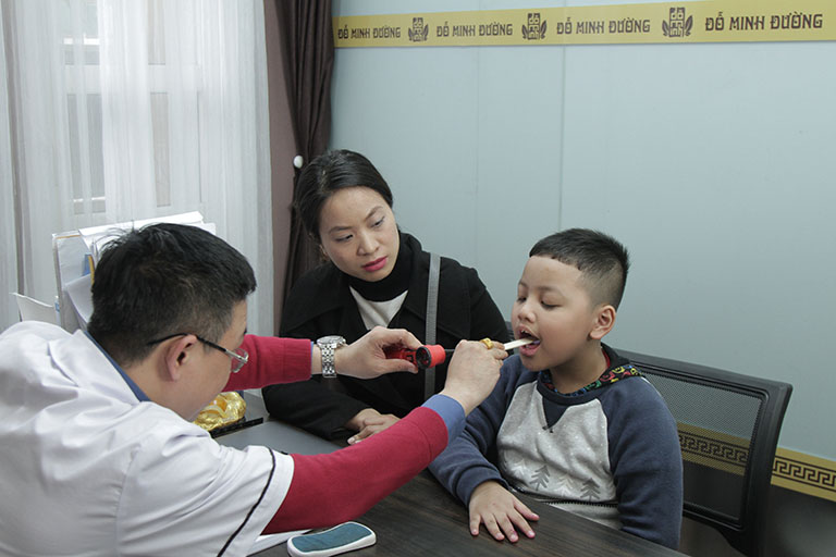 Lương y Tuấn đang kiểm tra cho một bệnh nhân nhỏ tuổi bị viêm họng
